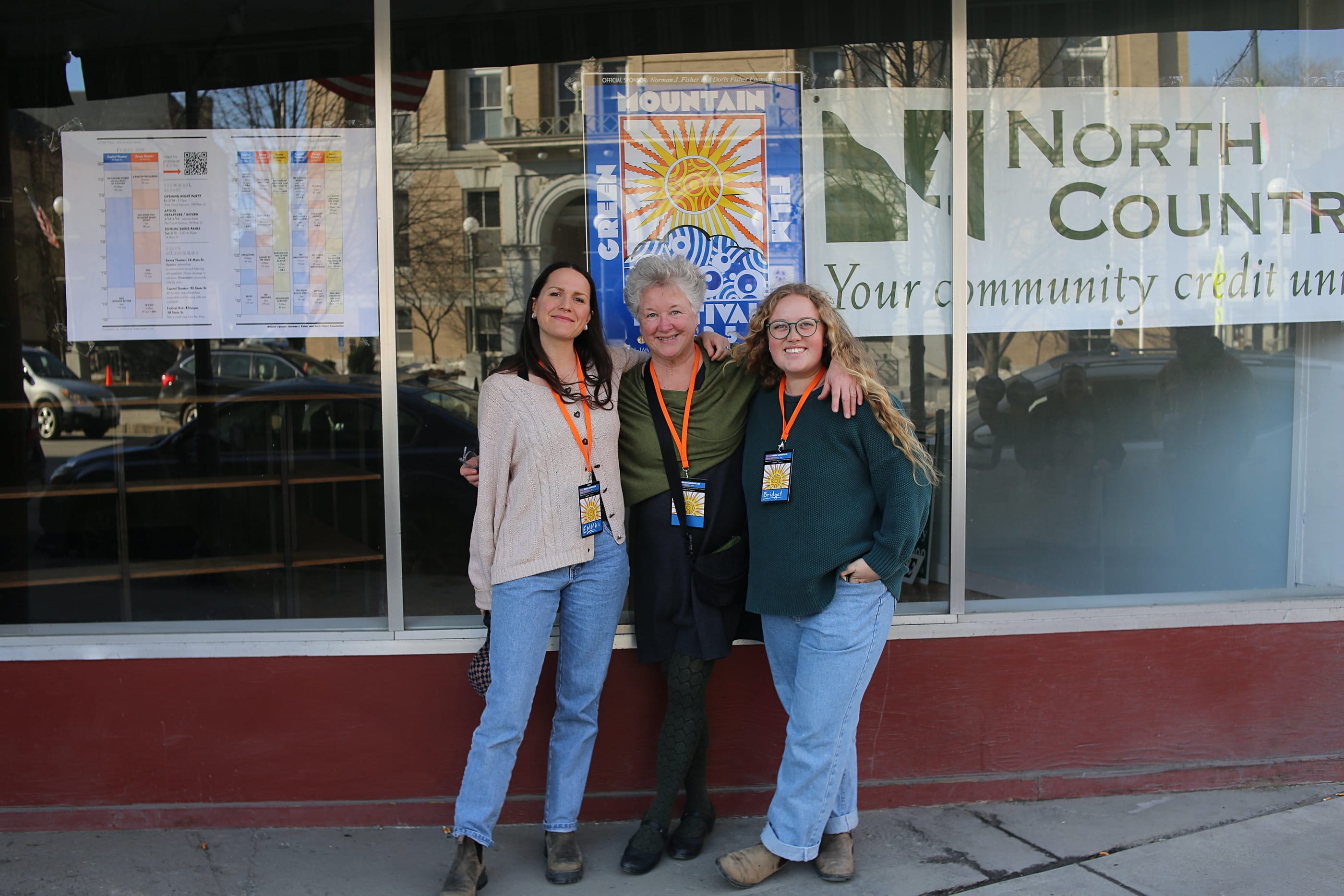 Three women stand in front of a storefront that displays GMFF signage.